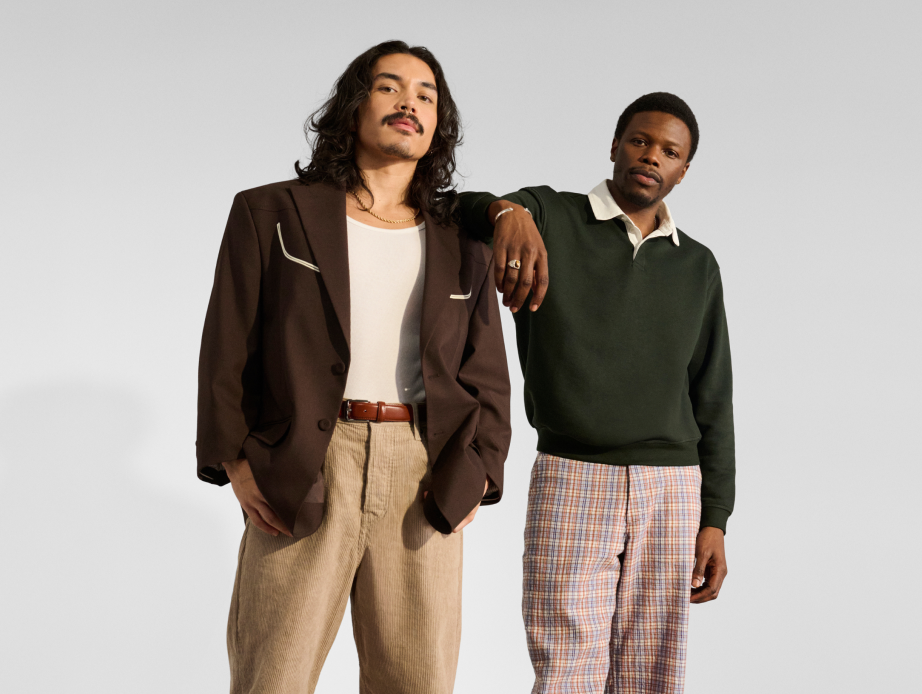 Person in a green sweater resting his arm on the shoulder of a man in a brown blazer